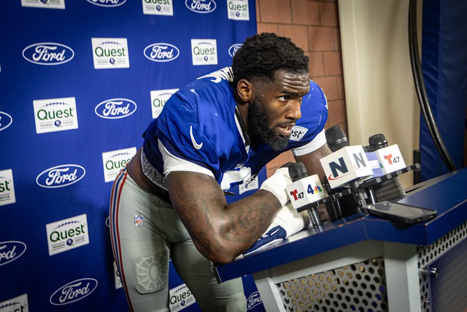 New York Giants linebacker Brian Burns (0) tries to catch his breath at the podium after he raced into the field house with linebacker Abdul Carter to speak to the media after a joint training camp practice with the New York Jets, Wednesday, August 13, 2025, in East Rutherford, N.J.