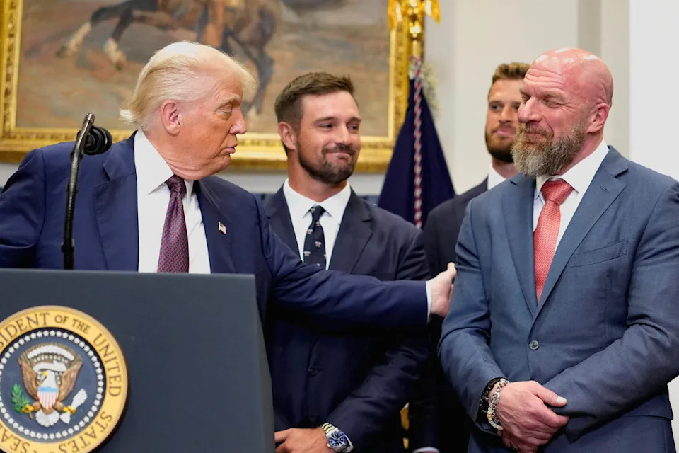 Donald Trump holds the arm of Triple H, while delivering remarks at the White House. / Kent Nishimura/Reuters
