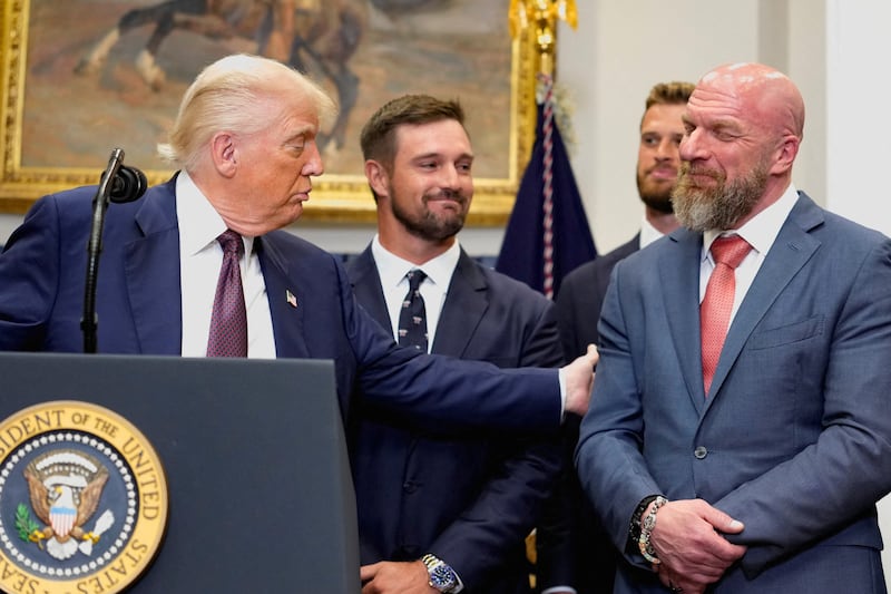 Donald Trump holds the arm of Paul Michael Levesque (Triple H), while delivering remarks at the White House.