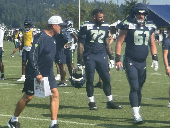 Run-game coordinator Rick Dennison (left), right tackle Abe Lucas (72) and center Jalen Sundell (61) at practice in Seattle Seahawks NFL training camp July 31, 2025, at the Virginia Mason Athletic Center in Renton. Gregg Bell/The News Tribune