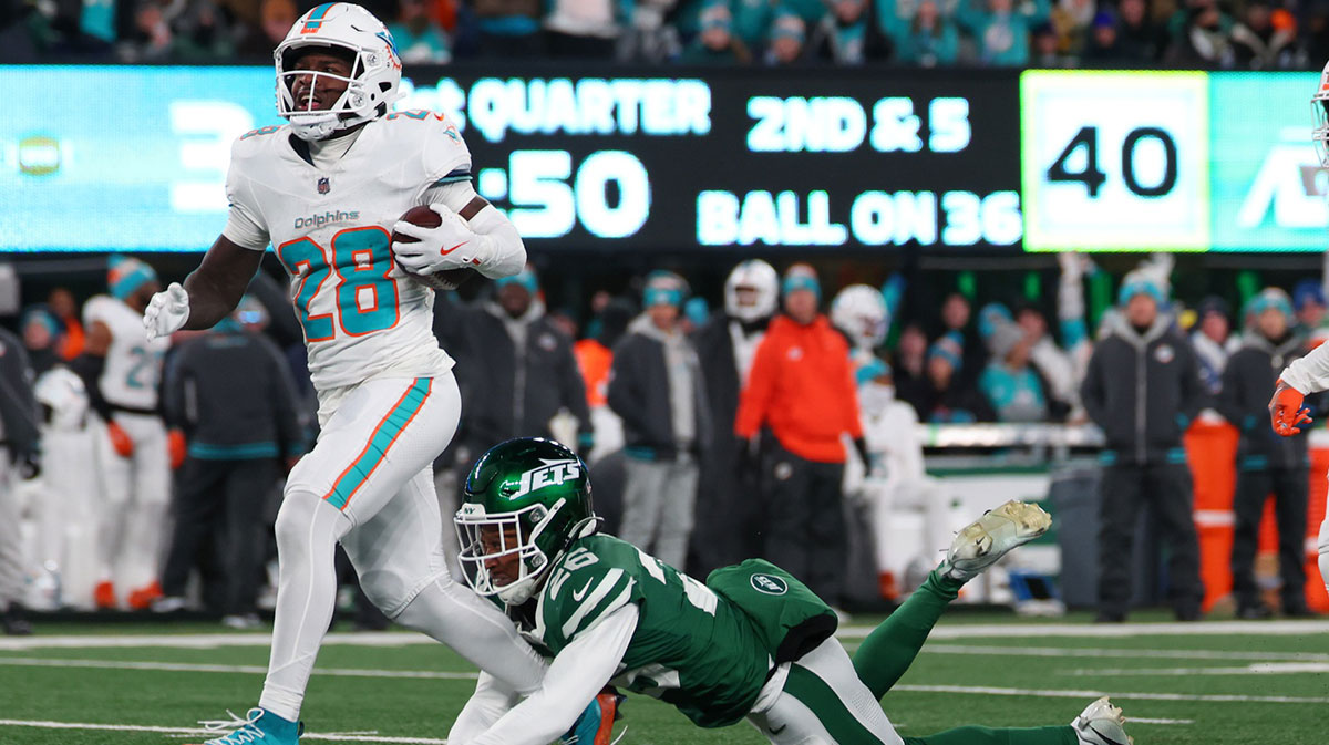 Miami Dolphins running back De'Von Achane (28) runs with the ball while avoiding a tackle attempt by New York Jets cornerback Brandin Echols (26) during the first quarter at MetLife Stadium. 