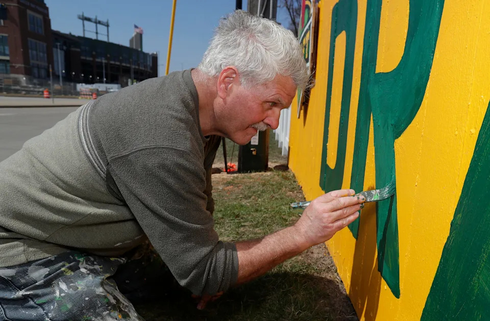 Christopher Handler paints the fence at 1167 Shadow Lane on April 11 in Green Bay celebrating the 2025 NFL Draft at Lambeau Field.
