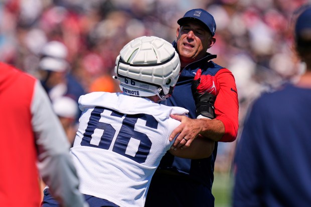 New England Patriots head coach Mike Vrabel, right, tangles with offensive tackle Will Campbell (66) during practice at the team's NFL football training camp, Wednesday, July 23, 2025, in Foxborough, Mass. (AP Photo/Charles Krupa)