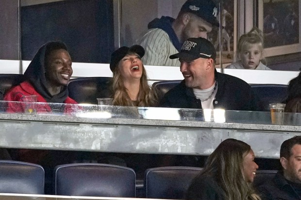 FILE - Travis Kelce, right, and Taylor Swift appear with actor-comedian Jerrod Carmichael, left, at Game 1 of the baseball AL Championship Series between the Cleveland Guardians and New York Yankees, Oct. 14, 2024, in New York. (AP Photo/Seth Wenig, File)