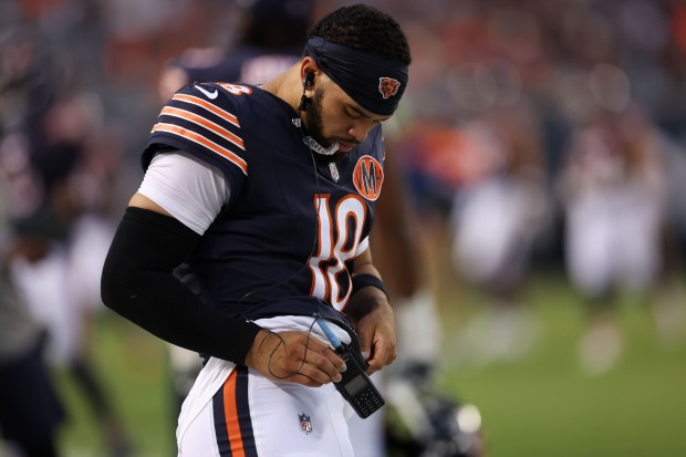 Chicago Bears quarterback Caleb Williams (18) puts on headset during...
