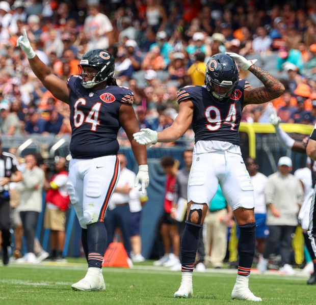 Chicago Bears defensive end Austin Booker (94) and Chicago Bears defensive tackle Jonathan Ford (64) celebrate Booker's sack of Miami Dolphins quarterback Zach Wilson (0) in the first half during a game at Soldier Field on Aug. 10, 2025, in Chicago. (Stacey Wescott/Chicago Tribune)