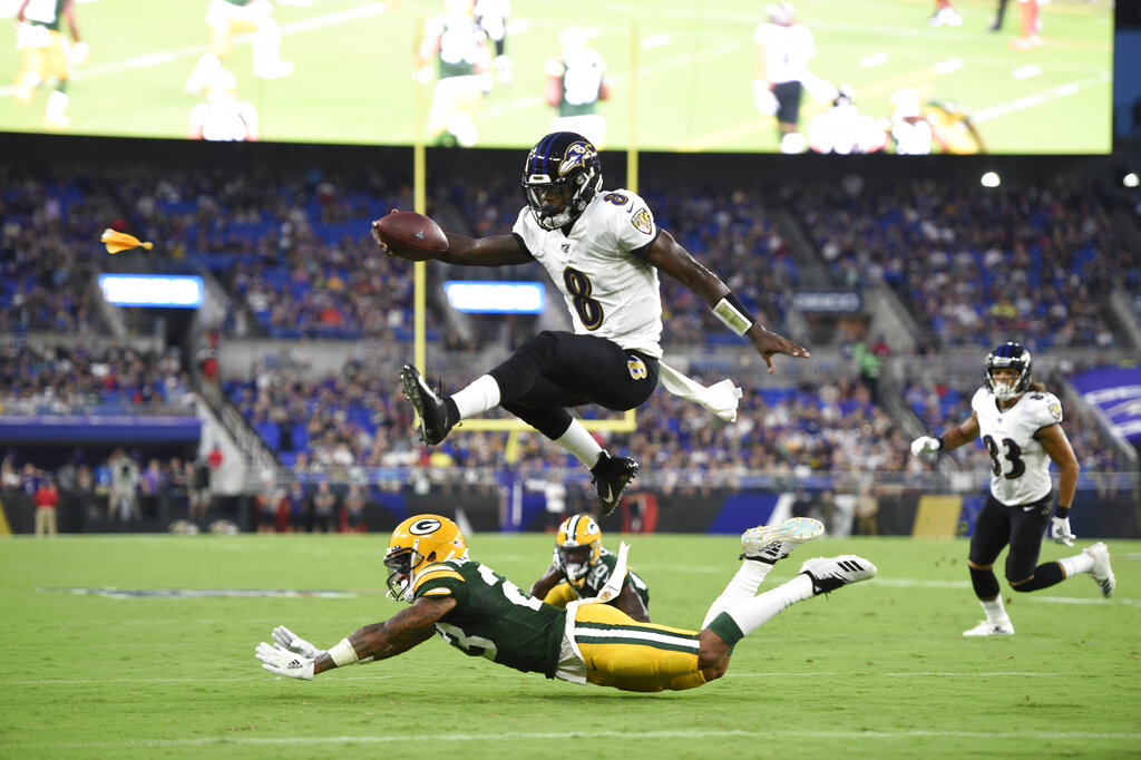 Baltimore Ravens quarterback Lamar Jackson (8) leaps over Green Bay Packers cornerback Jaire Alexander (23) during the first half of a NFL football preseason game, Thursday, Aug. 15, 2019, in Baltimore. The play was called back on a penalty on the Ravens. (AP Photo/Gail Burton)