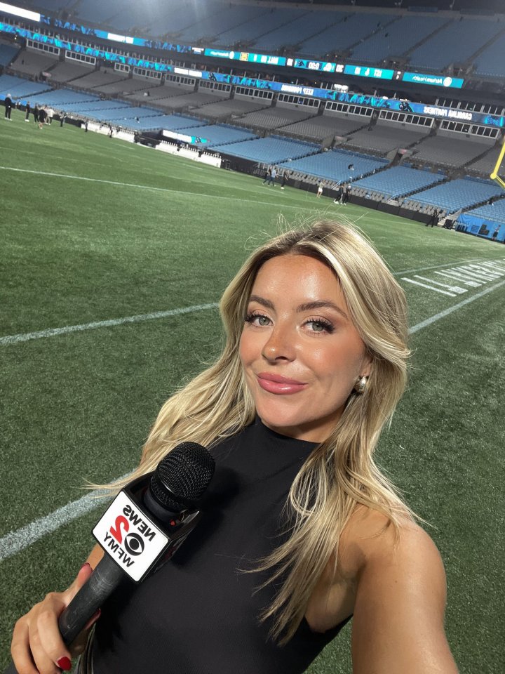Reporter holding microphone at football stadium.
