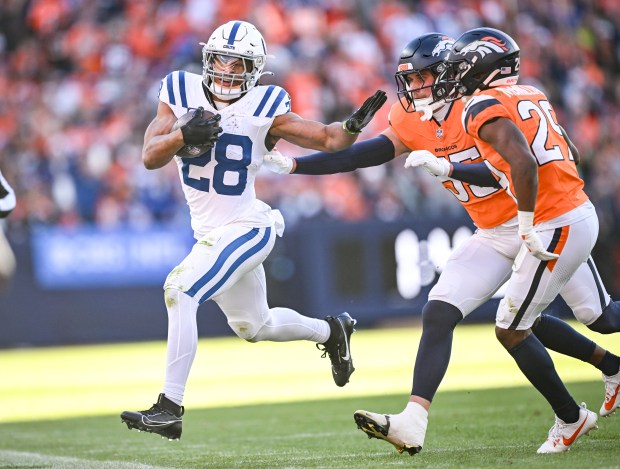 Jonathan Taylor (28) of the Indianapolis Colts rushes for a first down as Ja'Quan McMillian (29) and Cody Barton (55) of the Denver Broncos defend during the first quarter at Empower Field at Mile High in Denver on Sunday, Dec. 15, 2024. (Photo by AAron Ontiveroz/The Denver Post)