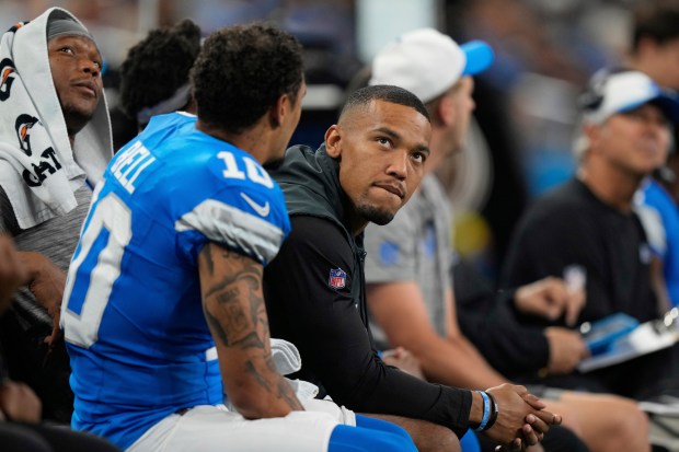 Detroit Lions wide receiver Amon-Ra St. Brown, right, sits on...