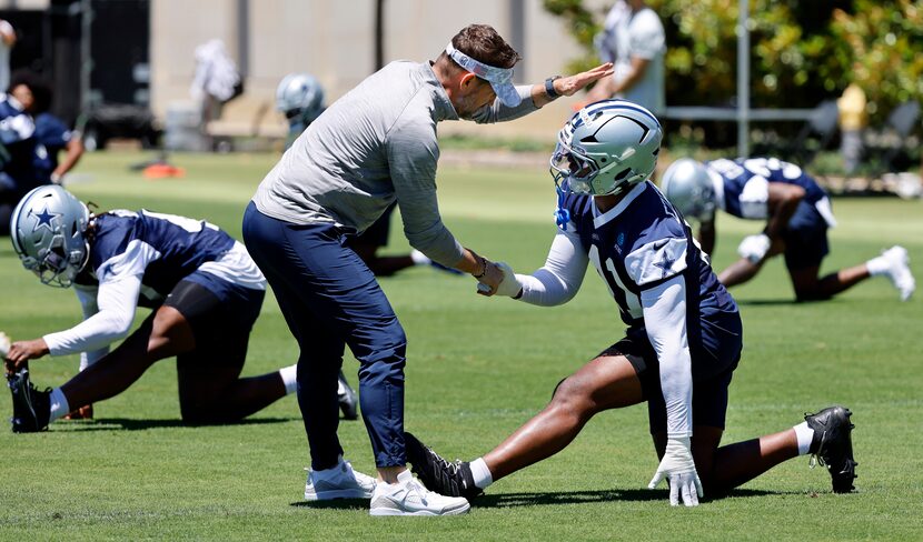 Dallas Cowboys head coach Brian Schottenheimer slaps hands with rookie defensive end Donovan...