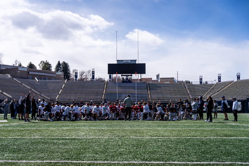 Utah State players take a knee to listen to USU head coach Bronco Mendenhall during spring football practice at Maverik Stadium in Logan, Utah.