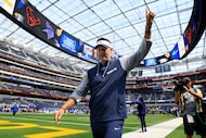 Dallas Cowboys head coach Brian Schottenheimer points to cheering fans as he walks off the...