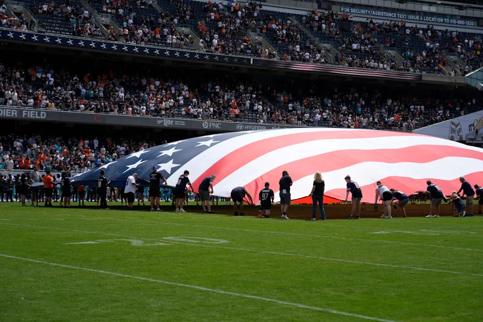 Aug 10, 2025; Chicago, Illinois, USA; People hold the flag during the national anthem before a game between the Chicago Bears and the Miami Dolphins at Soldier Field.David Banks-Imagn Images&period;