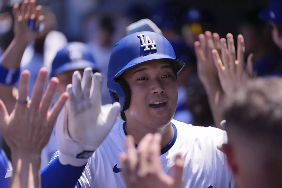 Los Angeles Dodgers' Shohei Ohtani is congratulated by teammates in the dugout after hitting a two-run home run during the third inning of a baseball game against the St. Louis Cardinals, Wednesday, Aug. 6, 2025, in Los Angeles. (AP Photo/Mark J. Terrill)