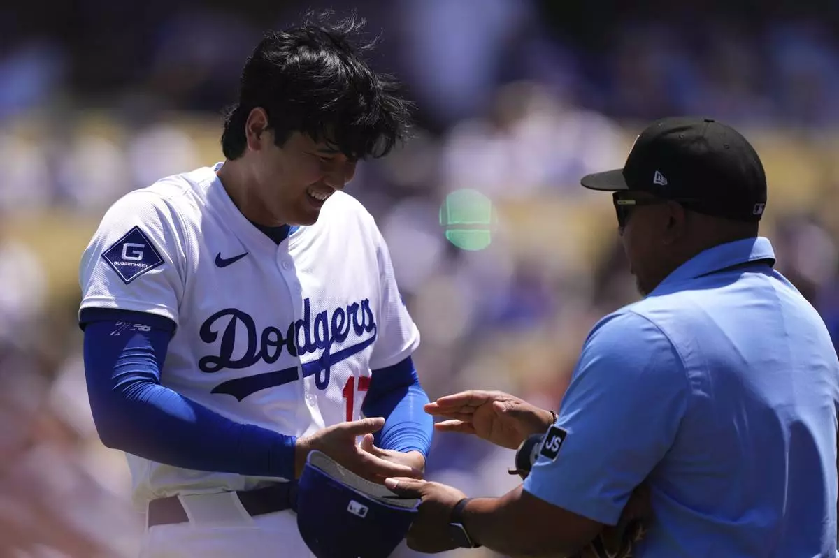 Los Angeles Dodgers' Shohei Ohtani, left, laughs while being checked by the third base umpire after pitching in the first inning of a baseball game against the St. Louis Cardinals, Wednesday, Aug. 6, 2025, in Los Angeles. (AP Photo/Mark J. Terrill)