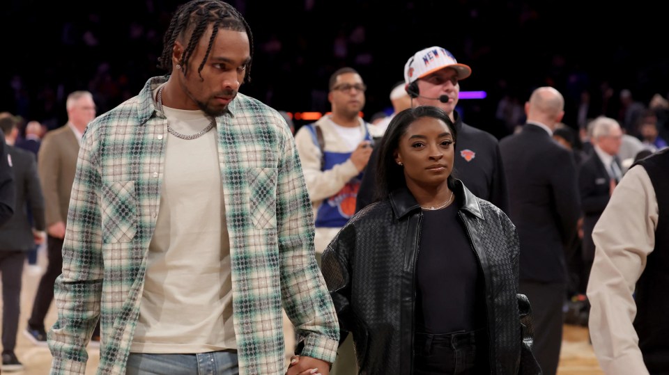 Simone Biles and Jonathan Owens holding hands at a basketball game.