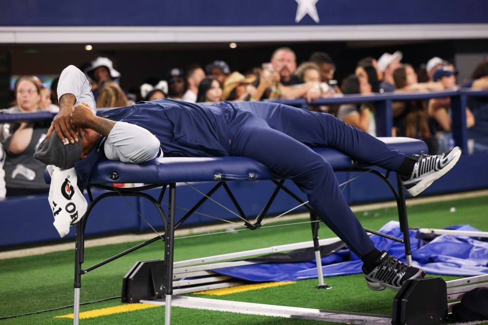 Micah Parsons of the Dallas Cowboys lying on a medical table during a game.