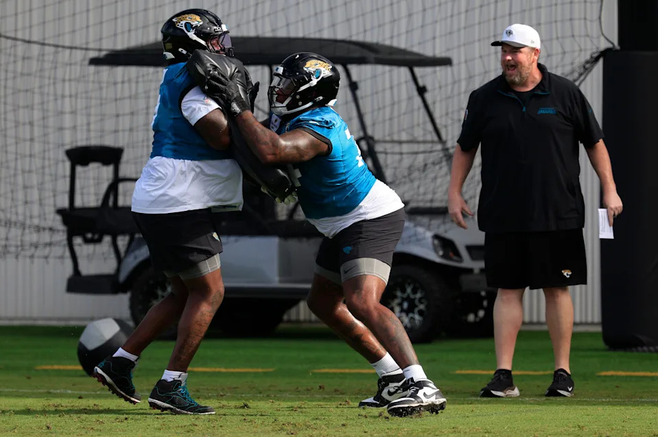 From left, Jacksonville Jaguars offensive tackle Anton Harrison (77) and lineman Fred Johnson (74) drill with blocking pads as offensive line coach Shaun Sarrett directs during an NFL training camp session at the Miller Electric Center, Friday, July 25, 2025, in Jacksonville, Fla. [Corey Perrine/Florida Times-Union]