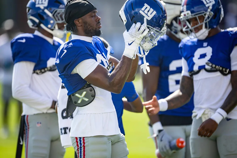 New York Giants cornerback Paulson Adebo (21) puts on his helmet during a joint training camp practice with the New York Jets, Wednesday, August 13, 2025, in East Rutherford, N.J.