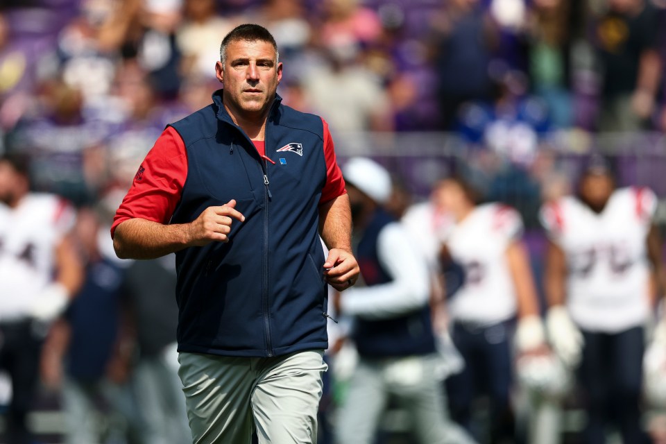 Mike Vrabel, coach of the New England Patriots, jogging on a football field.