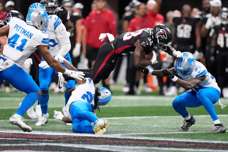 Atlanta Falcons running back being tackled by Detroit Lions defenders.