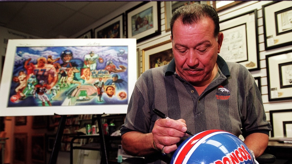 Lionel Taylor signs a helmet 