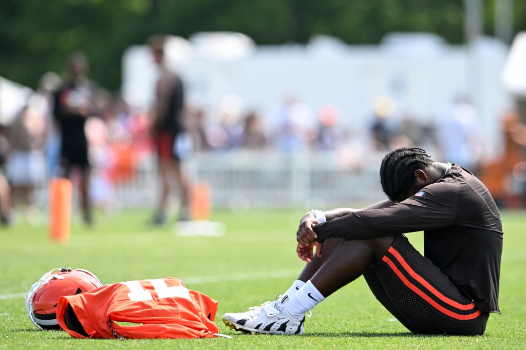 Cleveland Browns football player sitting on the field with his head down.