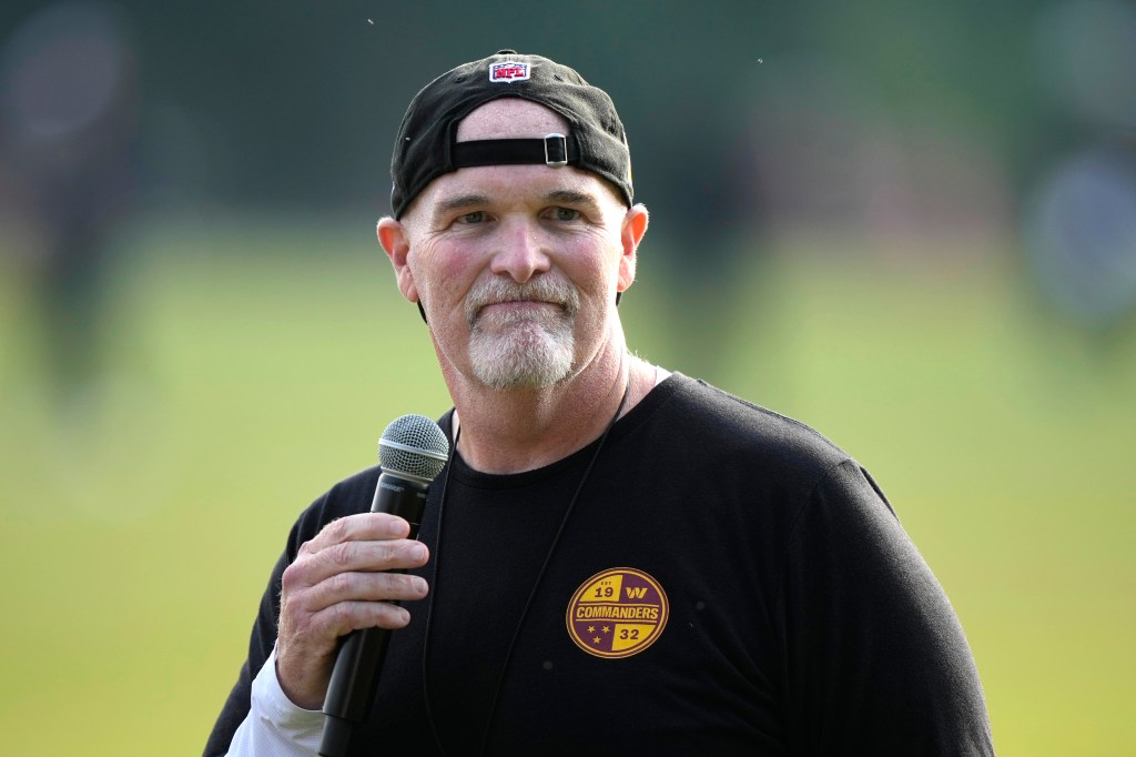 Dan Quinn, Washington Commanders head coach, speaking into a microphone.