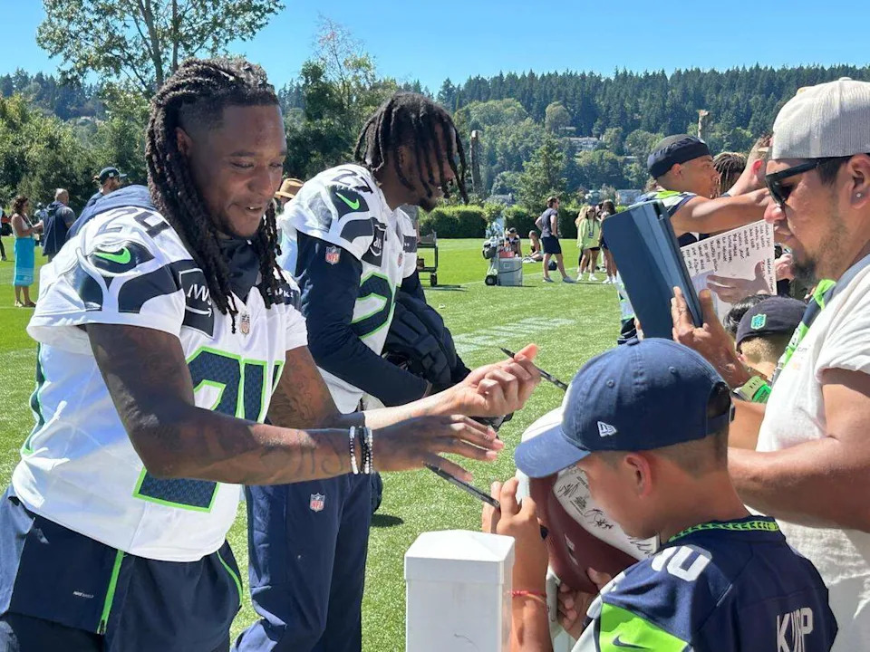 Cornerbacks Shaquill Griffin (24) and Riq Woolen (27) sign autographs for fans following the second practice of Seattle Seahawks NFL training camp Thursday, July 24, 2025, at the Virginia Mason Athletic Center in Renton.