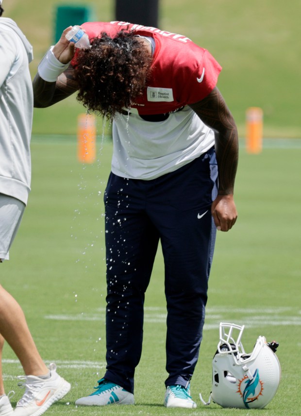 Miami Dolphins quarterback Tua Tagovailoa wets his hair during practice...