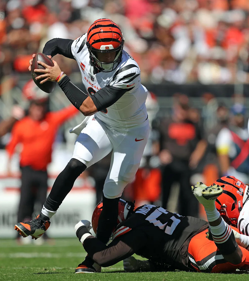 Cincinnati Bengals quarterback Joe Burrow (9) is tripped up by Cleveland Browns defensive end Isaiah McGuire (57) during the first half of an NFL football game at Huntington Bank Field, Sept. 7, 2025, in Cleveland, Ohio.