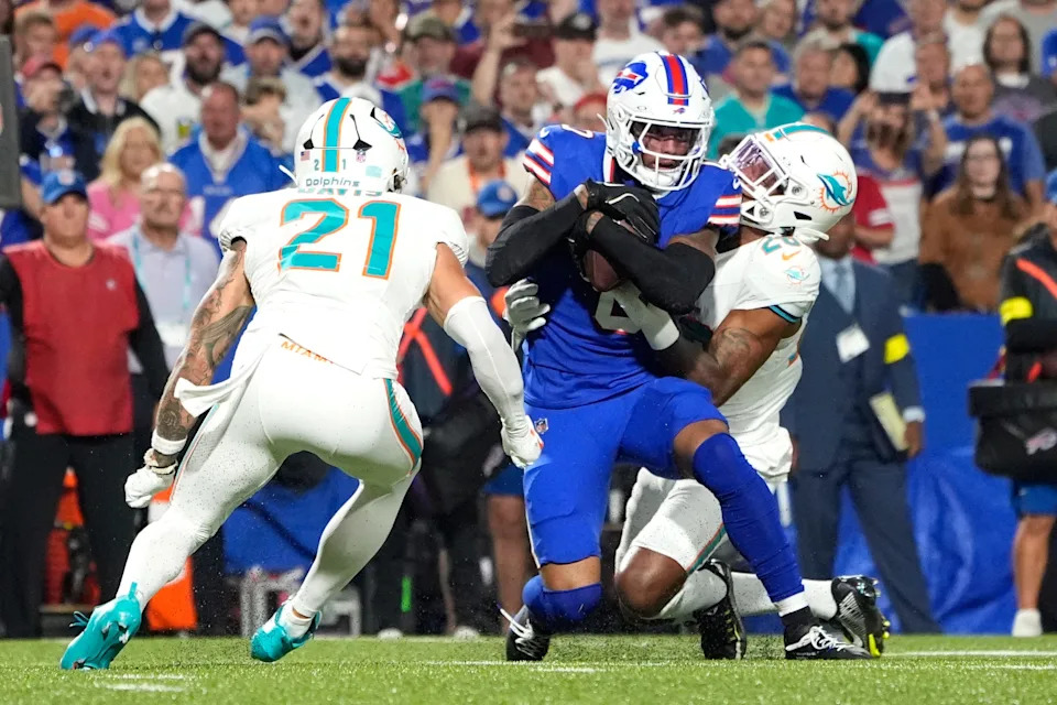 Sep 18, 2025; Orchard Park, New York, USA; Miami Dolphins running back de'von Achane (28) and safety Ashtyn Davis (21) tackle Buffalo Bills wide receiver Keon Coleman (0) in the second quarter at Highmark Stadium. Mandatory Credit: Gregory Fisher-Imagn Images