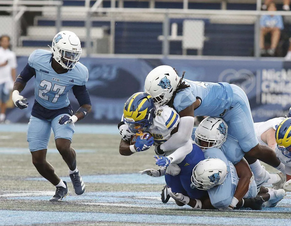 FIU Panthers defenders tackle Delaware Fightin' Blue Hens running back Viron Ellison Jr. (23) during football game on Saturday, September 20, 2025 at FIU Pitbull Stadium in Miami. Andrew Uloza / for Miami Herald