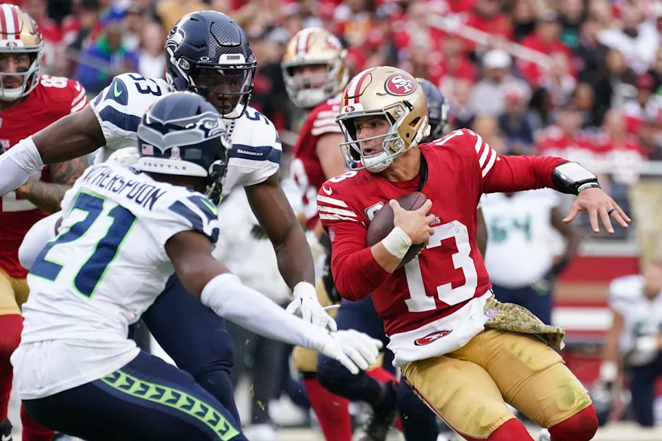 San Francisco 49ers quarterback Brock Purdy (13) scrambles away from Seattle Seahawks cornerback Devon Witherspoon (21) in the third quarter at Levi's Stadium Nov. 17, 2024, in Santa Clara, California.