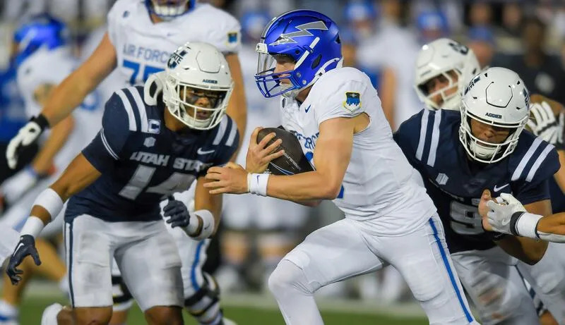 Air Force quarterback Liam Szarka (9) runs the ball as Utah State linebacker Bronson Olevao Jr. (14) and defensive tackle Tyree Morris (9) defend during the first half Saturday Sept. 13, 2025, in Logan, Utah. | Eli Lucero/Herald Journal
