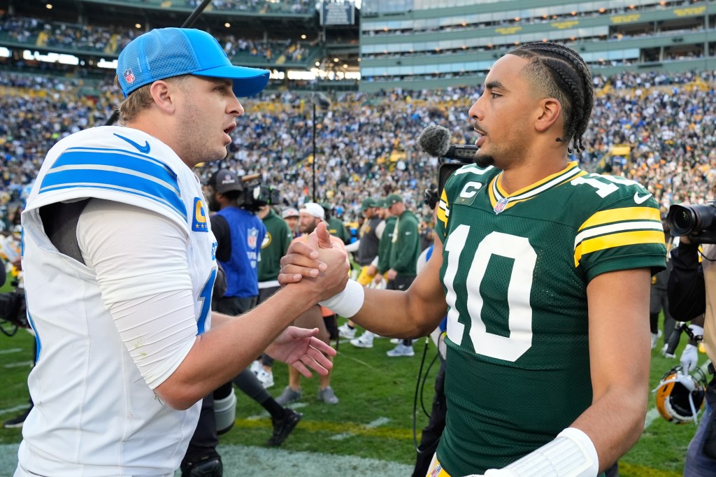 Two football players shaking hands on the field.