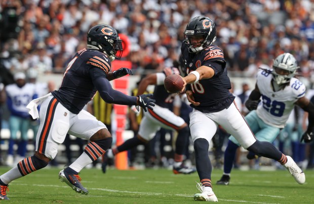 Chicago Bears quarterback Caleb Williams (18) hands off to running...