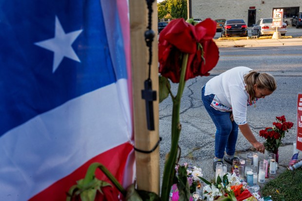 A woman lights a candle during a vigil, Sept. 15,...