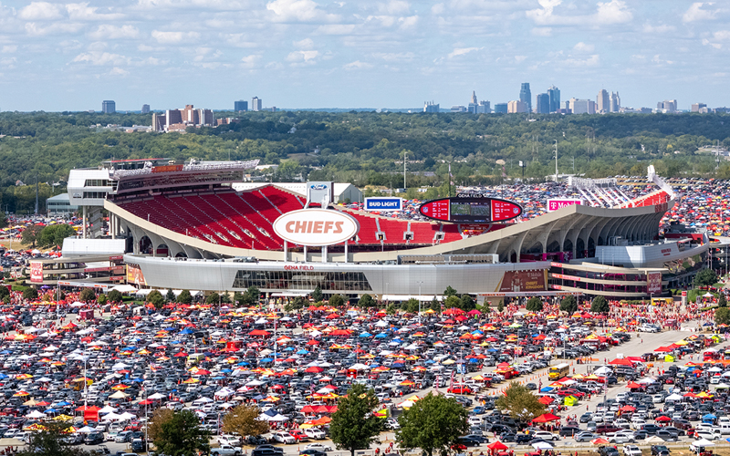 An aerial view of GEHA Field at Arrowhead Stadium with cars surrounding it during the day