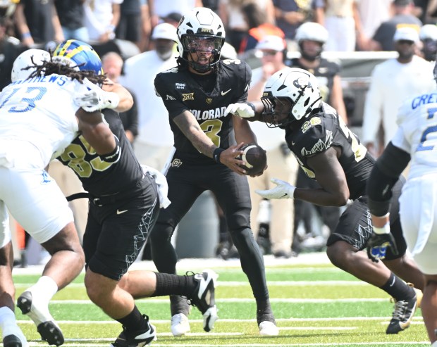 Colorado Buffaloes quarterback Kaidon Salter, center, hands off to running...