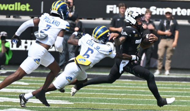 Colorado Buffaloes quarterback Kaidon Salter tries to escape Delaware's Kshawn...