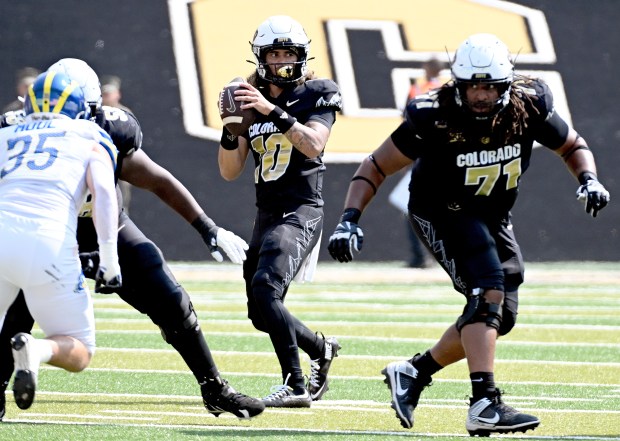 Colorado Buffaloes quarterback Julian Lewis, center, goes back to pass,...