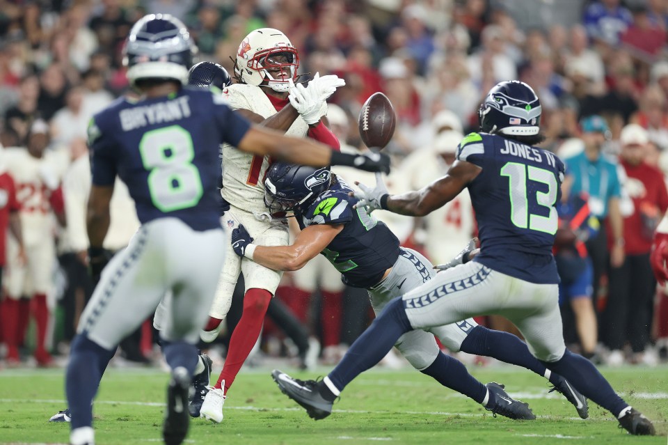 GLENDALE, ARIZONA - SEPTEMBER 25: Marvin Harrison Jr. #18 of the Arizona Cardinals drops the reception while being hit by Drake Thomas #42 of the Seattle Seahawks, allowing Ernest Jones IV #13 of the Seattle Seahawks to intercept during the first half of the game at State Farm Stadium on September 25, 2025 in Glendale, Arizona. (Photo by Christian Petersen/Getty Images)