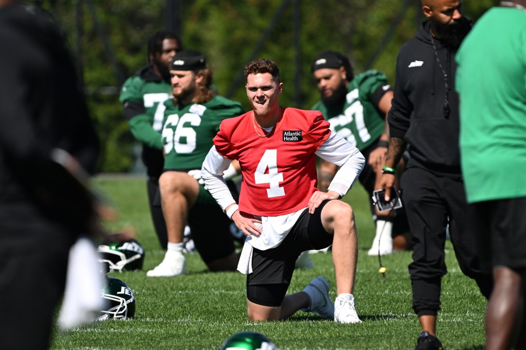 Brady Cook, wearing a red jersey with number 4, stretches during practice.