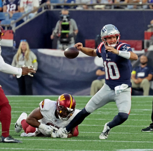 New England Patriots quarterback Drake Maye (10) unsuccessfully fends off Washington Commanders defensive tackle Jer'Zhan Newton (95) and fumbles the ball as the Patriots take on the Commanders. (Staff Photo By Stuart Cahill/Boston Herald)