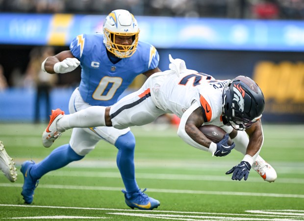RJ Harvey (12) of the Denver Broncos gets upended as Daiyan Henley (0) of the Los Angeles Chargers looks to make a tackle during the first quarter at SoFi Stadium in Inglewood, California on Sunday, Sept. 21, 2025. (Photo by AAron Ontiveroz/The Denver Post)