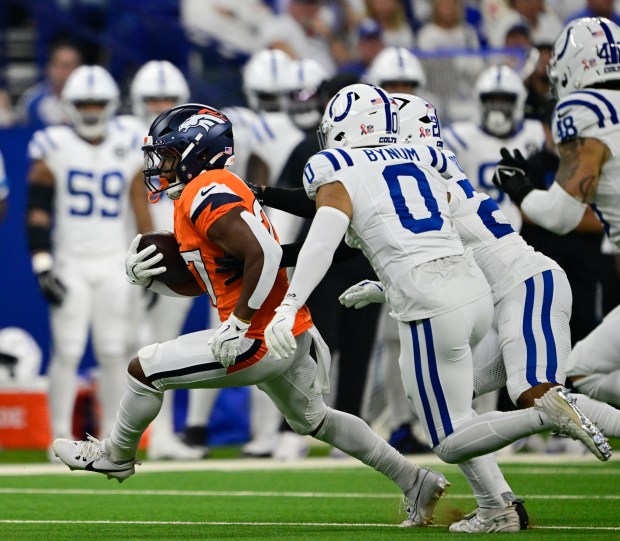 Denver Broncos running back J.K. Dobbins (27) finds a hole against Indianapolis Colts safety Cam Bynum (0) and safety Nick Cross (20) in the first quarter at Lucas Oil Stadium in Indianapolis, Indiana, on Sunday, Sept. 14, 2025. (Photo by Andy Cross/The Denver Post)