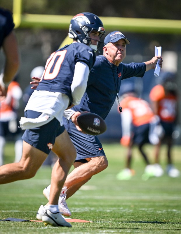 Head coach Sean Payton of the Denver Broncos runs as Bo Nix (10) prepares to make a handoff during training camp at Broncos Park in Centennial on Tuesday, Aug. 12, 2025. (Photo by AAron Ontiveroz/The Denver Post)