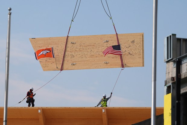 Workers guide the final structural beam into place during a topping out ceremony for the Denver Broncos' new NFL football training facility in Centennial on Friday, Aug. 1, 2025. (AP Photo/David Zalubowski)